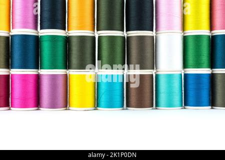 Fadenröhrchen für Nähgarn haben viele Farben und sind auf weißem Hintergrund platziert. Stockfoto