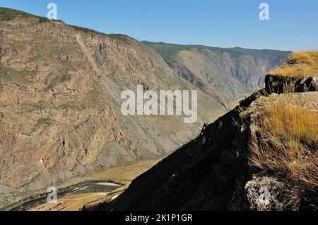 Blick von der Spitze des Berges auf einen tiefen Canyon und einen gewundenen Fluss, der im Frühherbst darunter fließt. Chulyshman Flusstal, Altai, Sibirien, Russ Stockfoto