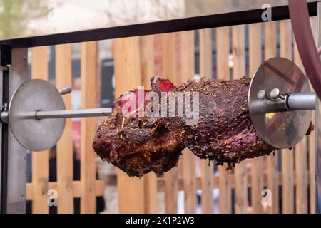 Prozess des Kochens großer Fleischstücke auf Spieß über offenem Feuer Stockfoto