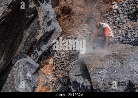 Südkonawe, Indonesien. 19. September 2022. Ein Steinminer verbrennt einen großen Stein, der mit einem Hammer leicht zu brechen ist. Traditioneller Steinabbau, der von den Bewohnern des Dorfes Sanggula durchgeführt wird. Traditionelle Bergleute, die übrigens Anwohner sind, verkaufen ihre Arbeit in der Regel an Bergbauunternehmen. Kredit: SOPA Images Limited/Alamy Live Nachrichten Stockfoto