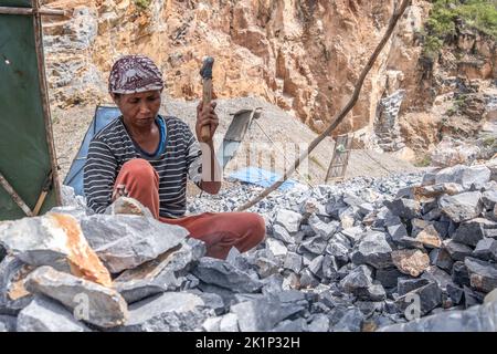 Südkonawe, Indonesien. 19. September 2022. Eine Bergarbeiterin zerbricht einen Stein in kleine Stücke. Traditioneller Steinabbau, der von den Bewohnern des Dorfes Sanggula durchgeführt wird. Traditionelle Bergleute, die übrigens Anwohner sind, verkaufen ihre Arbeit in der Regel an Bergbauunternehmen. Kredit: SOPA Images Limited/Alamy Live Nachrichten Stockfoto