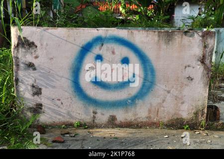 Bild oder Illustration eines blauen Lächelns mit Sprühfarbe an der Wand Stockfoto