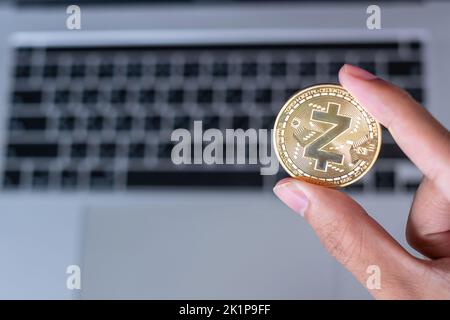 Geschäftsmann Hand hält Golden Zcash (ZEC) Kryptowährung Münze über Laptop-Tastatur, Crypto ist digitales Geld im Blockchain-Netzwerk, verwendet Stockfoto