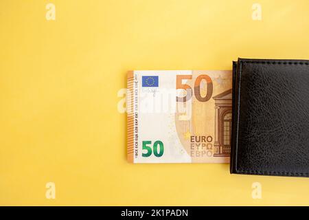 Fünfzig Euro-Banknoten in einer schwarzen Brieftasche auf gelbem Hintergrund Stockfoto