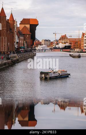 Danzig Polen Mai 2022 touristische Schifffahrt Altstadt in Danzig. Das Schiff mit Touristen fährt auf der Granary Island Reflection in Moltawa River Cityscap zu einer Kreuzfahrt am Flussufer ab. Uralter Kran. Besuchen Sie Danzig Poland Travel Destination. Touristenattraktion Stockfoto