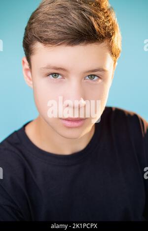 Selbstbewusster Typ. Teenager-Lifestyle. Inspiration für Unabhängigkeit. Nahaufnahme Porträt eines ambitionierten Jungen in schwarzem T-Shirt, der auf blauem Backgro isoliert auf die Kamera schaut Stockfoto