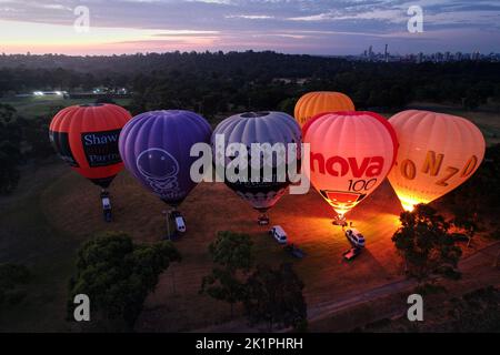 Eine Gruppe von Heißluftballons, die bei Sonnenuntergang mit dem Schein des Feuers abheben Stockfoto