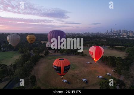 Eine Gruppe von Heißluftballons, die bei Sonnenuntergang mit dem Schein des Feuers abheben Stockfoto