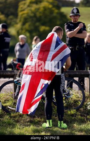 Ein Mitglied der Öffentlichkeit mit einer Unionsflagge, als der Sarg von Königin Elizabeth II. Durch Runnymede führt, auf seiner Reise vom State Funeral in Westminster Abbey, London, zu einem Einbindungdienst in der St. George's Chapel in Windsor Castle, Bekshire. Bilddatum: Montag, 19. September 2022. Stockfoto