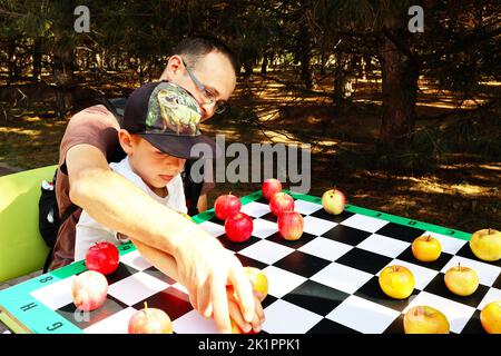 Vater und Sohn spielen Steine mit roten und grünen Äpfeln Stockfoto