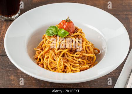 Spaghetti mit Bolognese-Sauce auf weißem Porzellanteller auf Holztisch Stockfoto