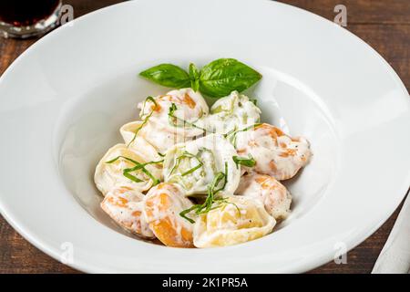 Verschiedene Arten von Pelmeni oder russischen Knödeln in weißer Platte auf Holzgrund Stockfoto