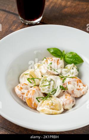 Verschiedene Arten von Pelmeni oder russischen Knödeln in weißer Platte auf Holzgrund Stockfoto