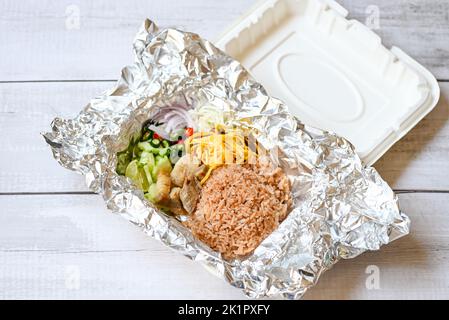 Thai-Lebensmittel auf Box mit Aluminiumfolie Lebensmittelverpackung Essen zum Mitnehmen - Reis gemischt mit Garnelenpaste gebratener Reis auf Box, Reis gewürzt mit Garnelenpaste Rezept, r Stockfoto