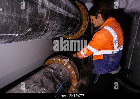 Arbeiter, die ein Wasserrohrleitungssystem in einem technischen Tunnel installieren Stockfoto