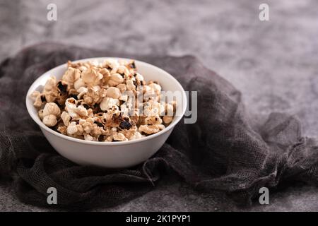 In der kleinen weißen Schüssel auf Keramik verbranntes Popcorn Stockfoto