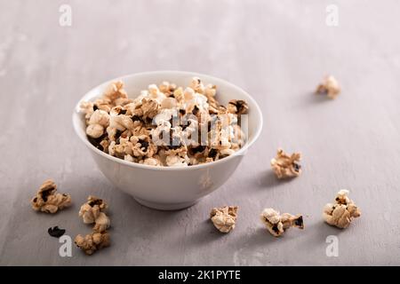 In der kleinen weißen Schüssel auf Keramik verbranntes Popcorn Stockfoto