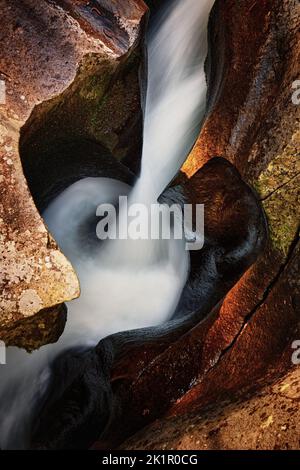 Eine szenische vertikale Aufnahme eines Wasserfalls, der mit einem starken Strom die Felsen herabfällt Stockfoto