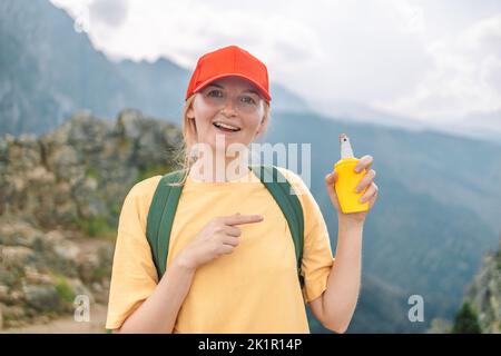 Frau, die Insektenschutzmittel gegen Moskito und Zecke auf ihre Hand während der Wanderung in der Natur Gipfel Berg. Hautschutz gegen Insektenstich Stockfoto