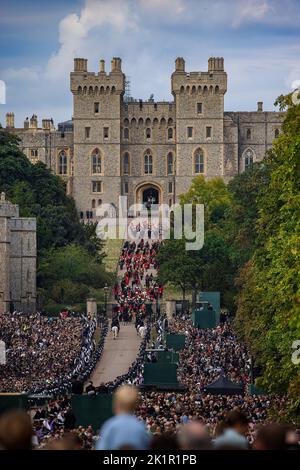 Die Königin kehrt zum letzten Mal nach dem Staatsfuneral in der Westminster Abbey in ihr geliebtes Haus Windsor Castle zurück. Riesige Menschenmengen säumten den langen Spaziergang, um sich von Ihrer Majestät zu verabschieden, als der staatliche Leichenwagen langsam an ihnen vorbeiging. Die Prozession betrat das Schlossgelände über den langen Spaziergang. Stockfoto