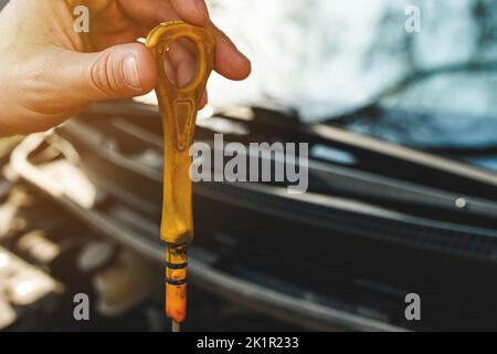 Schmutziger gelber Griff von einem Automotor-Messstab in der Hand Stockfoto