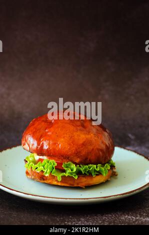 Draufsicht auf Burger mit Garnelen, Fleischpastete, Salat, Tomate auf schwarzem Hintergrund. Blaue Platte. Essen und Lifestyle. Fast Food Stockfoto