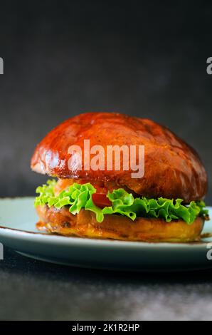 Draufsicht auf Burger mit Garnelen, Fleischpastete, Salat, Tomate auf schwarzem Hintergrund. Blaue Platte. Essen und Lifestyle. Fast Food Stockfoto