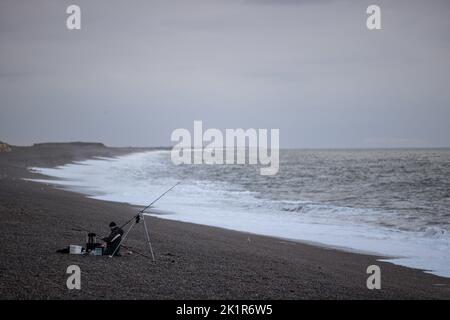 Ein Mann wird gesehen, Angeln auf Weybourne Beach, Norfolk während der Bank Holiday Montag 19. September 2022. Stockfoto