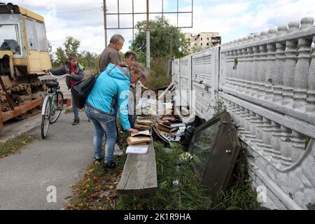 IZIUM, UKRAINE - 19. SEPTEMBER 2022 - die Menschen sehen sich die Bücher an, die unter den Trümmern eines Wohnhauses in Izium, das befreit wurde, geborgen wurden Stockfoto