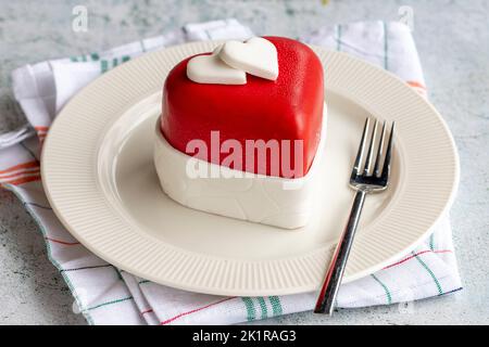 Herzförmige Torte im besonderen Design. Design Kuchen auf grauem Hintergrund. Nahaufnahme Stockfoto