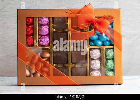 Verpackte Geschenkschokolade. Gepackte Pralinen auf grauem Hintergrund. Nahaufnahme Stockfoto