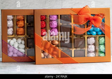 Verpackte Geschenkschokolade. Gepackte Pralinen auf grauem Hintergrund. Nahaufnahme Stockfoto