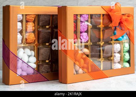 Verpackte Geschenkschokolade. Gepackte Pralinen auf grauem Hintergrund. Nahaufnahme Stockfoto
