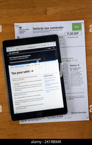 Eine Form V11 Vehicle Tax Reminder Notice von der Driver & Vehicle Licensing Agency. Die DVLA-Website wird auf einem ipad angezeigt. Stockfoto
