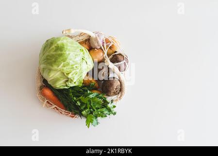 Saitenbeutel mit Zutaten für die Zubereitung von ukrainischem Borscht auf weißem Hintergrund. Draufsicht Stockfoto