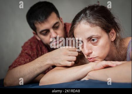 Ein Mann und eine Frau streiten sich auf dem Bett in der Wohnung. Sie sind schlecht gelaunt, weil sie Liebesprobleme haben. Stockfoto