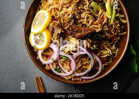 Hyderabadi Mutton Goat Biryani serviert mit Joghurt Raita in stimmungsvoller Umgebung Stockfoto