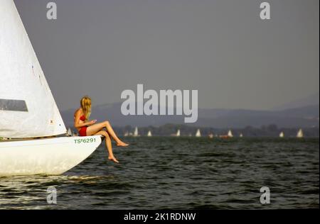 Frau auf dem Bug des Segelbootes, Chiemsee, Oberbayern, Deutschland Stockfoto