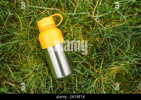 Nahaufnahme von Edelstahl-Thermoskannen auf grünem Gras mit Kopierraum. Stockfoto