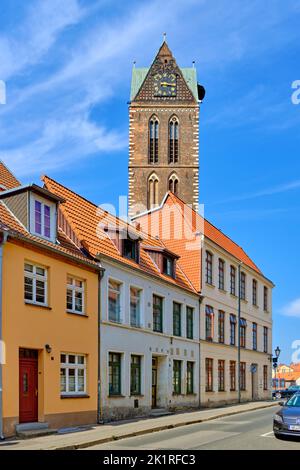 Turm und Kirchturm der ruinierten Marienkirche und Anordnung der Häuser in der Papenstraße, Altstadt der Hansestadt Wismar, Deutschland. Stockfoto