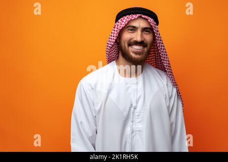 Porträt eines jungen lächelnden arabischen Mannes auf orangefarbenem Hintergrund Stockfoto