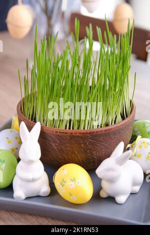Osterdekor für Zuhause. Grüner Hafer, dekorative Kaninchen und Eier Stockfoto