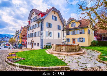 Der steinerne Brunnen mit einer kleinen Skulptur auf der Säule im Innenhof der Pfarrkirche St. Leodegar in Luzern, Schweiz Stockfoto