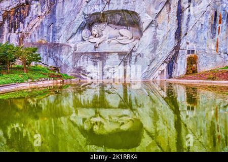 Denkmal des Löwen von Luzern und seine Spiegelungen im Wasser des Gedächtnistnisses Teich, Luzern, Schweiz Stockfoto