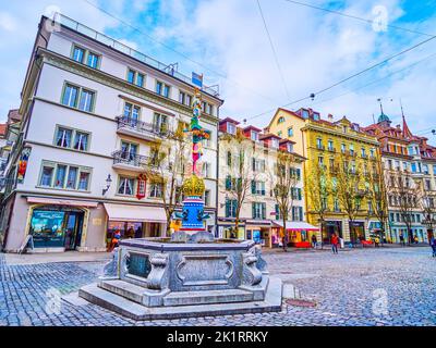 LUZERN, SCHWEIZ - 30. MÄRZ 2022: Das Stadtbild von Luzern mit buntem Fritschi-Brunnen im Vordergrund, am 30. März in Luzern, Schweiz Stockfoto