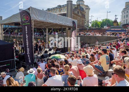 Menschen, die Live-Musik genießen, die auf der Center Stage der Cascade Steps während des Bristol Harbour Festivals 2022 in England, Großbritannien, aufgeführt wird. Stockfoto