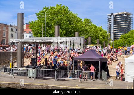 Menschen, die Live-Musik genießen, die auf der Center Stage der Cascade Steps während des Bristol Harbour Festivals 2022 in England, Großbritannien, aufgeführt wird. Stockfoto