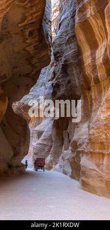 Eine vertikale Aufnahme eines Wagens, der einen schmalen Pfad zwischen den Wänden des Petra Canyon, Jordanien, passiert Stockfoto