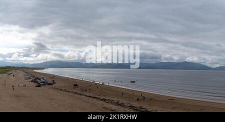 Inch Strnad, Irland - 5. August 2022: Panoramalandschaft von Inch Strand in der Bucht von Dingle mit vielen Autos und Strandbesuchern an einem bewölkten Sommertag Stockfoto