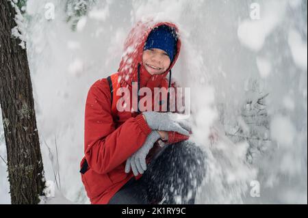 Porträt eines Jungen im Teenageralter, der im Winter im Wald schneit und spaßig ist Stockfoto